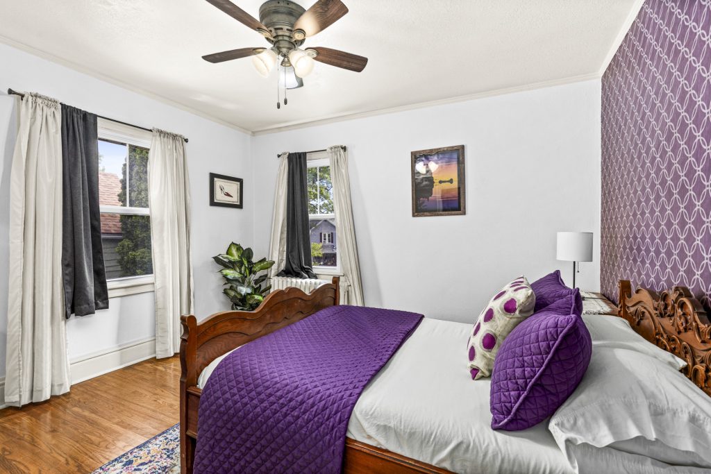 The purple bedroom is a full sized bed with an antique bed frame.