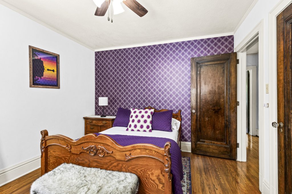 Purple bedroom with an antique carved wood bed frame.