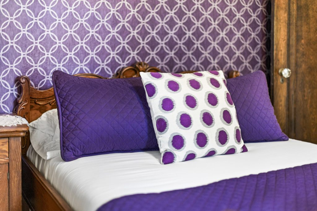 Purple bedding and accent pillows on a queen bed.