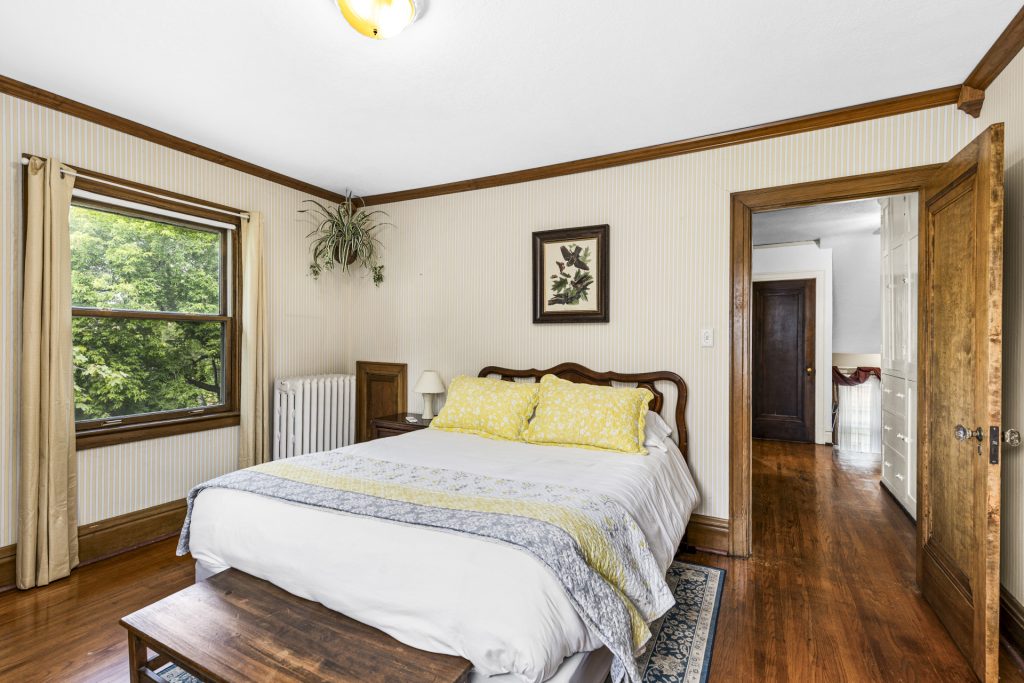 Sunny bedroom with original woodwork and hardwood floors.
