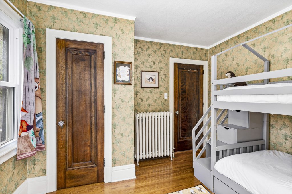 Kids bunk room with a twin trundle and vintage wallpaper.