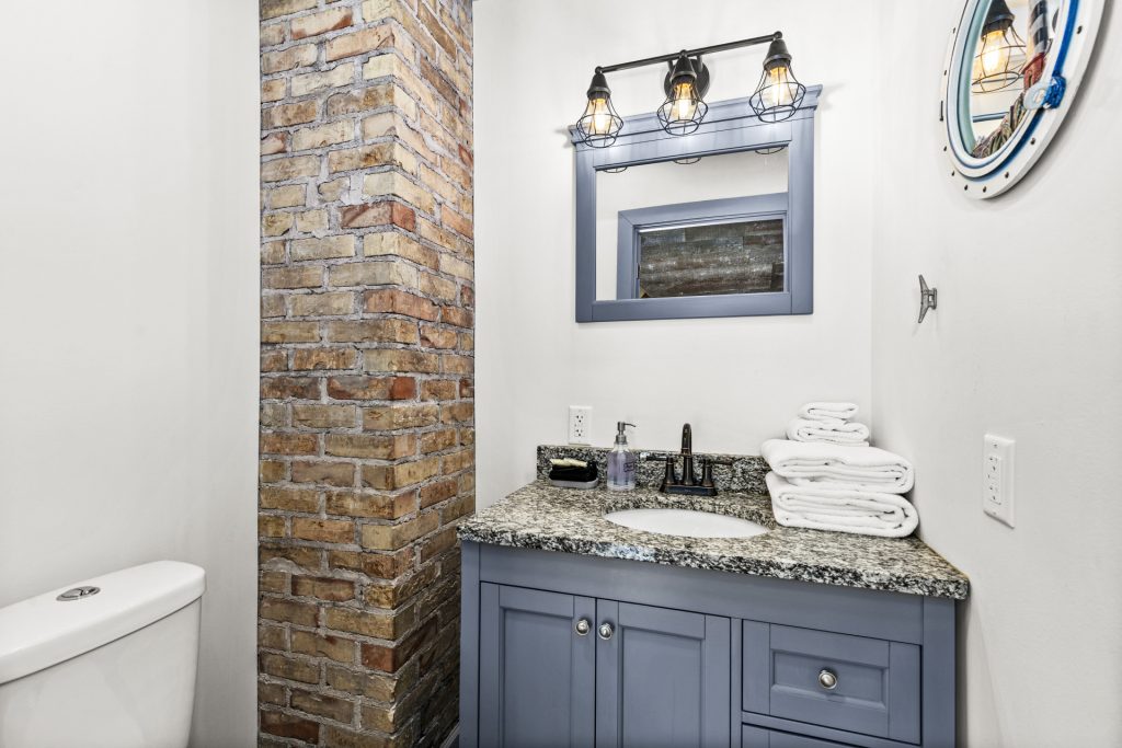 Third floor bath with exposed brick and a stone vanity.