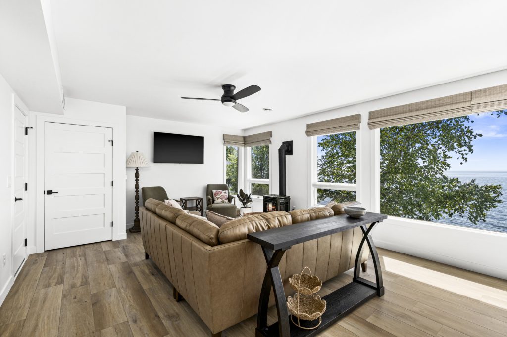 A comfortable living area with plush seating, a wall mounted TV, and big windows that pull in the lake light.