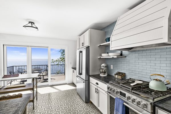 The chef's kitchen features a professional gas range, custom hood, and bright tilework, all just steps from sweeping lake views.