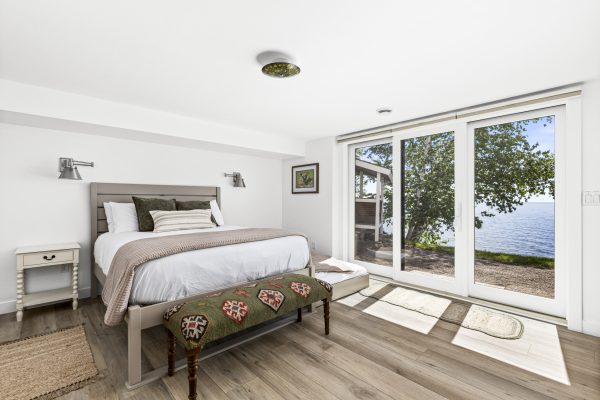The green bedroom features a queen bed with lakeside views and direct access to the outdoors.