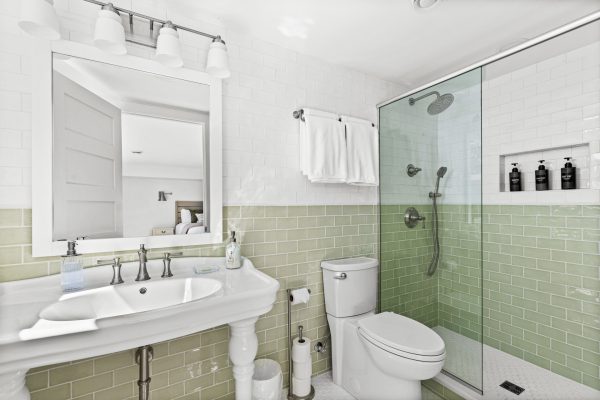 A walk in glass shower and vanity complete the green bedroom's spa inspired ensuite bath.