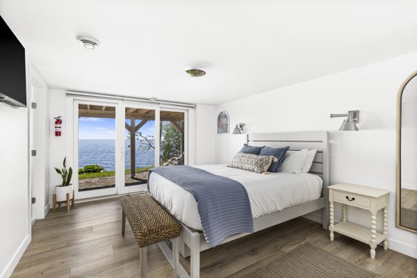 The blue bedroom offers a queen bed with direct lake views and walkout access to the outdoors.