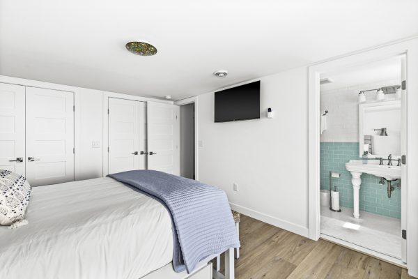 The blue bedroom includes ample closet space, a wall mounted TV, and a bright ensuite just steps away.