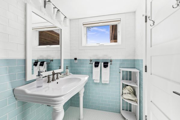 The ensuite features bright aqua tile, a shower tub combo, and clean modern fixtures.